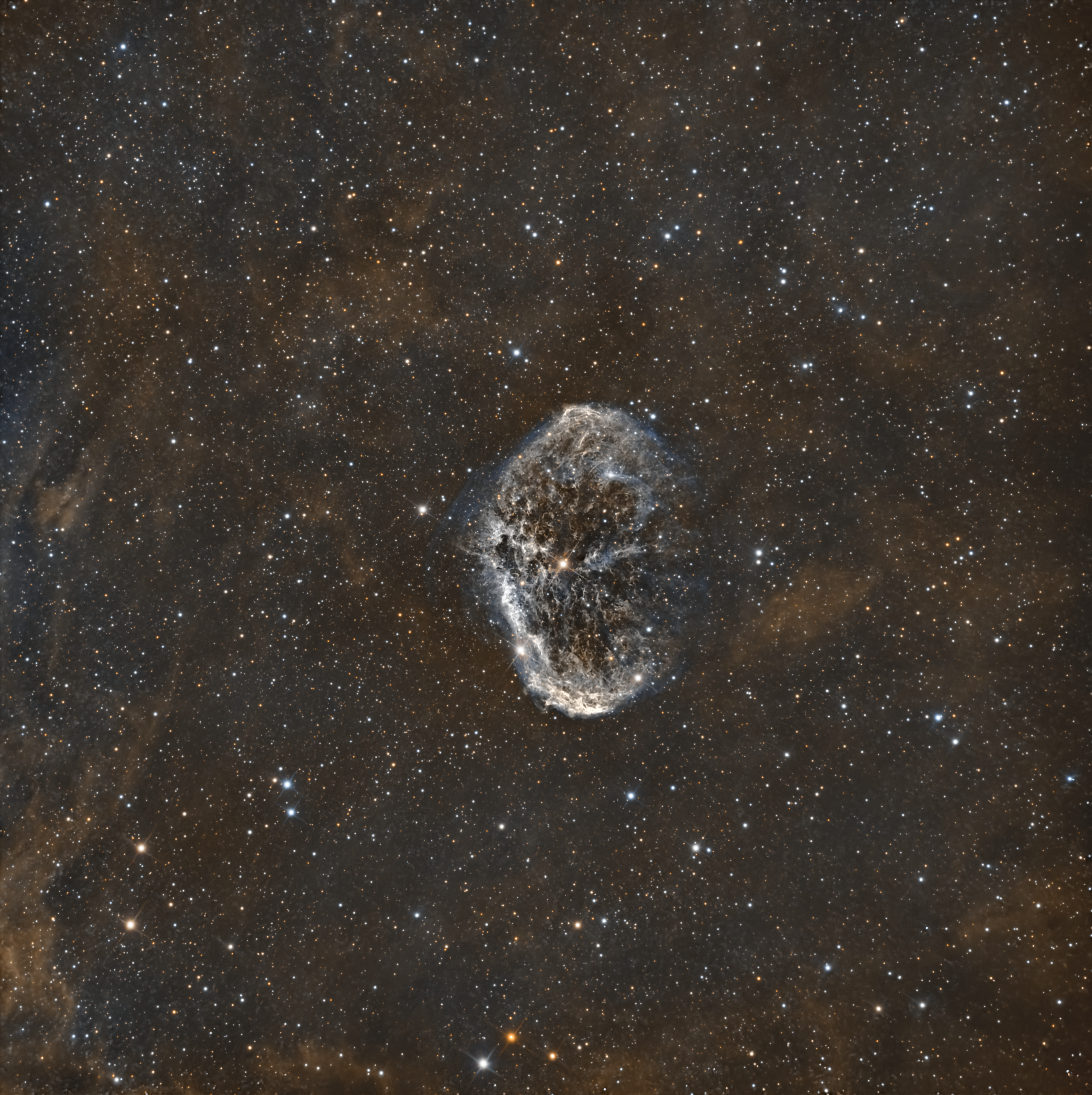 High-resolution image of the Crescent Nebula (NGC 6888), showing a bright, curved shell of glowing hydrogen and oxygen gas surrounded by faint, wispy filaments in the Cygnus region of the Milky Way.